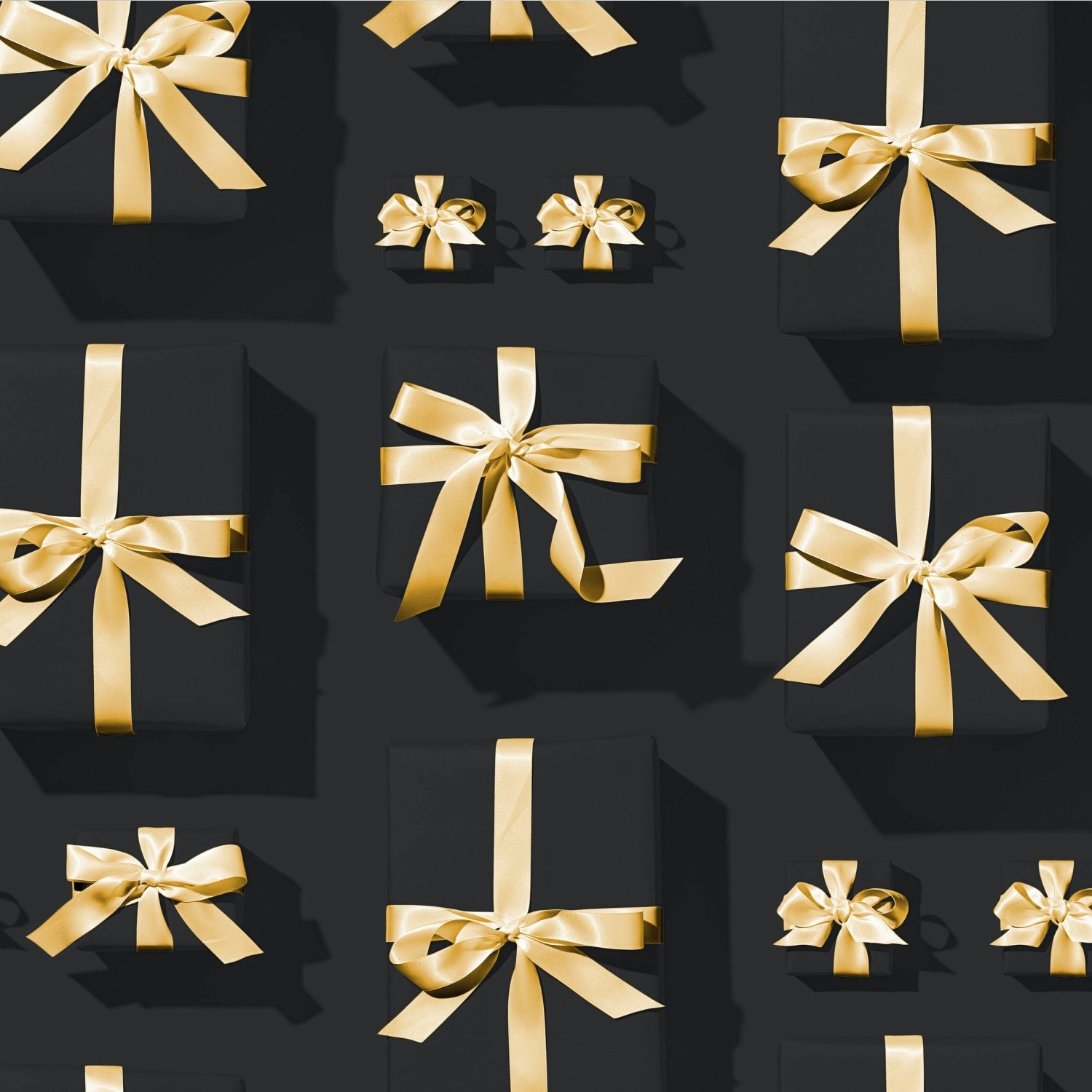 Verschieden große Geschenke in schwarzem Geschenkpapier mit einer Schleife aus goldenem Geschenkband
