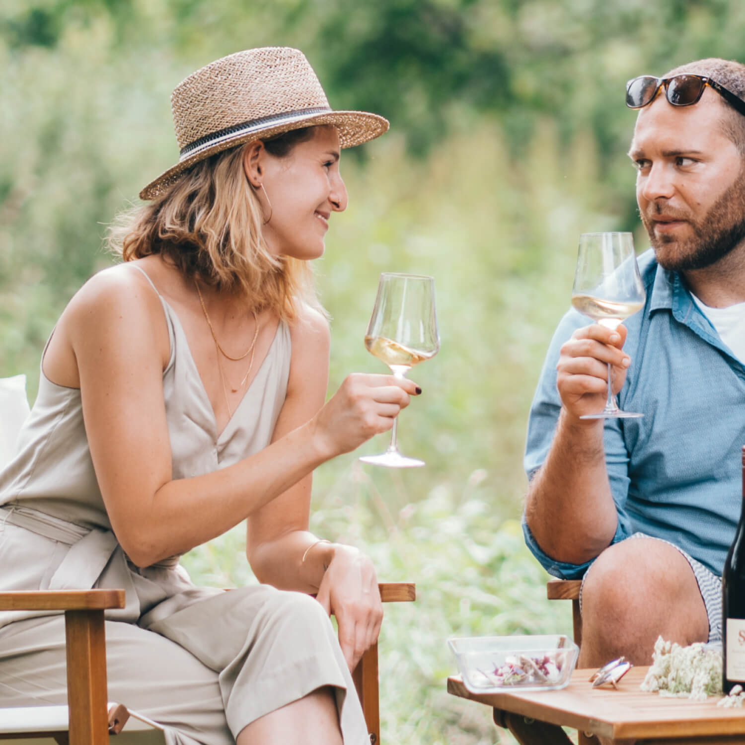Zwei Personen, welche sich mit einem Glas Schaumwein im Garten anstoßen