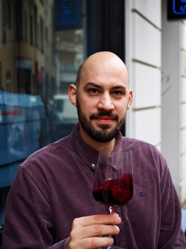 Der Vertriebmitarbeiter Philipp, lächelnd mit einem Glas Rotwein