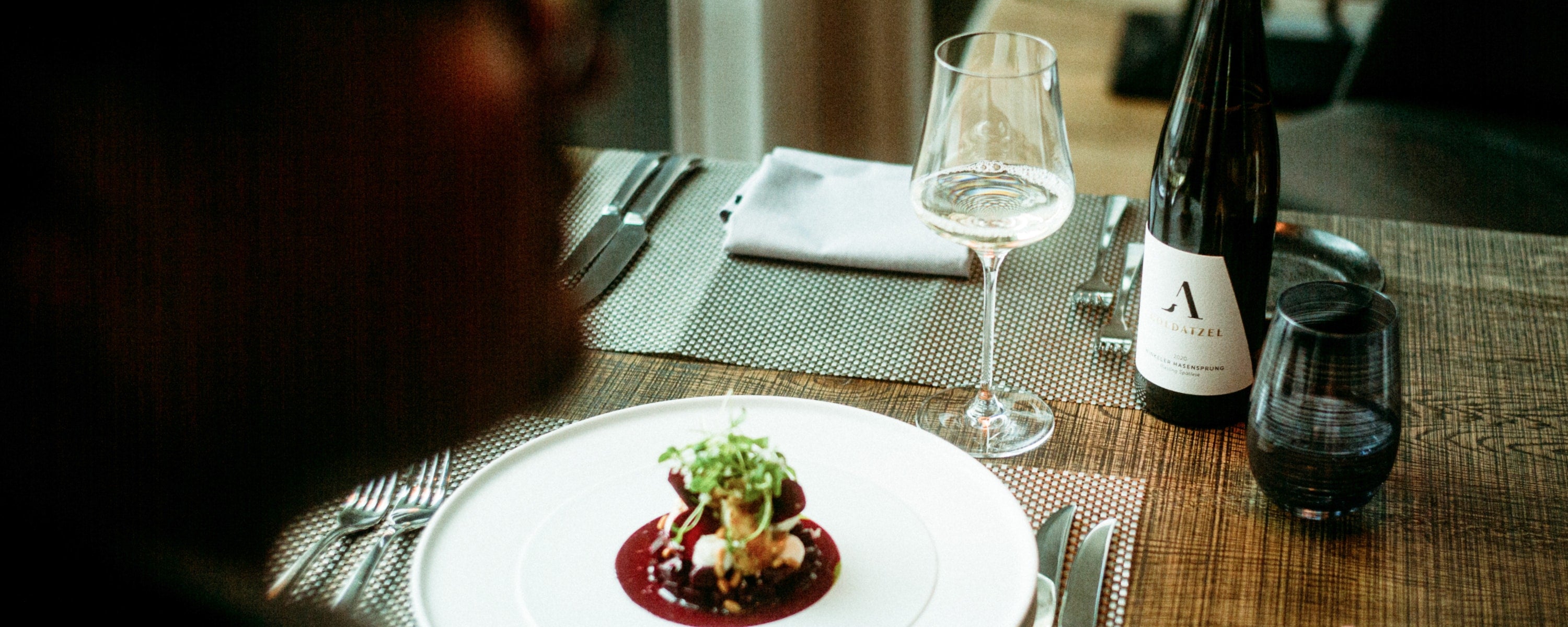 Ein gedeckter Restauranttisch im Ritzi mit einem Weinglas und einer Flasche Wein des Weingutes Goldatzel
